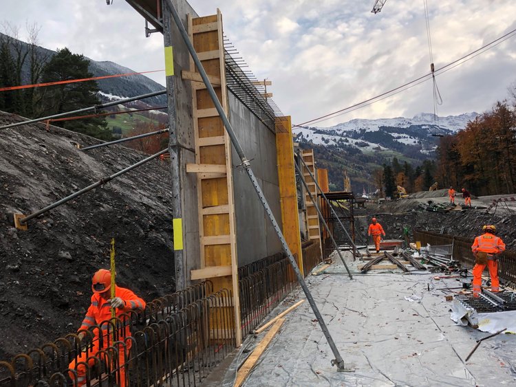 Emergency access road to RUAG. Photo: several workers on the construction site; concrete walls of the emergency access road built on the slope side.