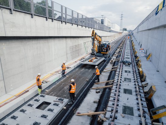 Slab Track Austria im Einsatz Mehrere Bauarbeiter auf einer Schienenbaustelle in der Stadt